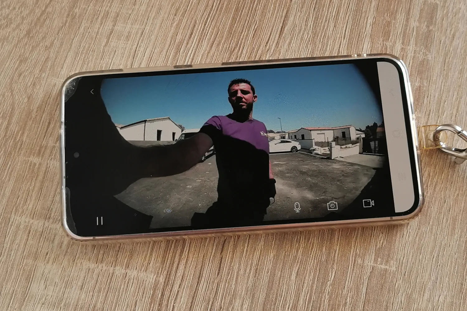 Smartphone affichant le retour vidéo en direct d'un visiophone connecté devant une maison à Saint-Gelais.